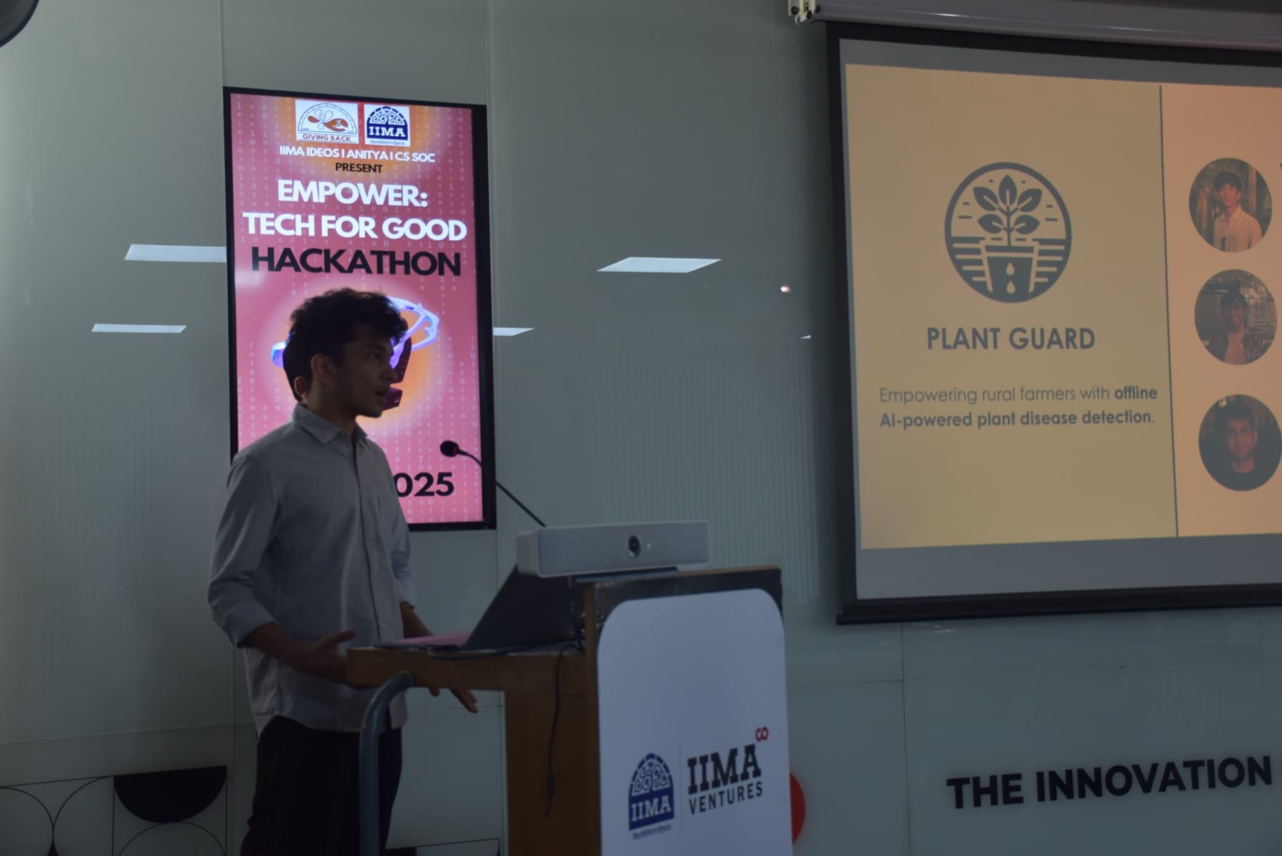 Vatsalya presenting at a podium beside a slide reading “Plant Guard: Empowering rural farmers with offline AI-powered plant disease detection”, with an EMPOWER: Tech for Good Hackathon 2025 banner behind him.